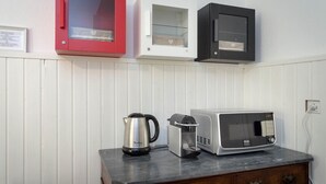 Una cocina con encimera de mármol, cafetera, tostadora y tres armarios en rojo, blanco y negro.