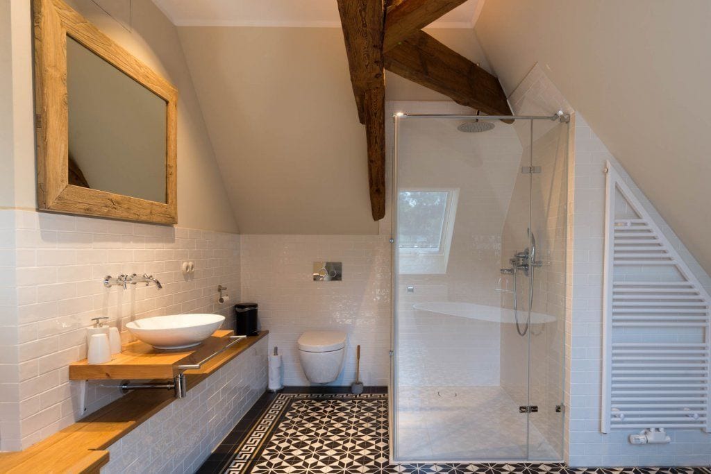 A modern bathroom with a freestanding bathtub, a large mirror, a toilet, and a glass-enclosed shower.