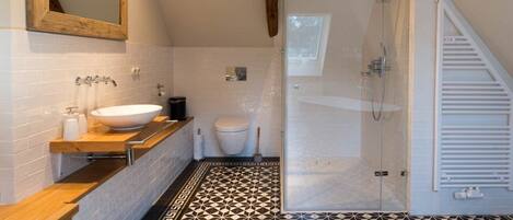 A modern bathroom with a freestanding bathtub, a large mirror, a toilet, and a glass-enclosed shower.