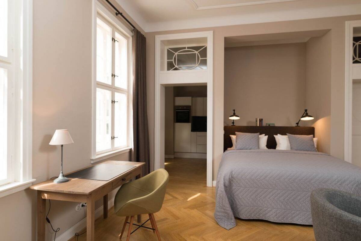 Une chambre avec un lit, un bureau, une chaise et une vue sur la cuisine.