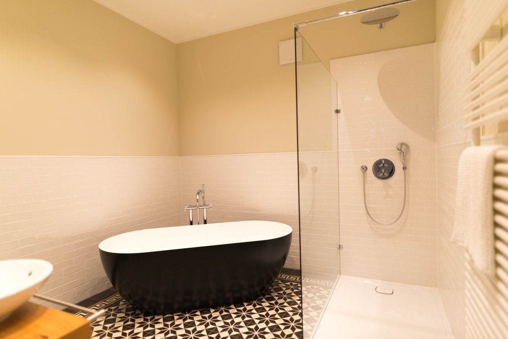 A modern bathroom with a freestanding bathtub, a glass-enclosed shower, and a patterned floor.