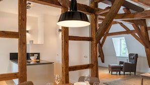 A dining area with a wooden ceiling, a table set for four, and a chair in the background. - Schloss Beuchow (Lübbenau/Spreewald)