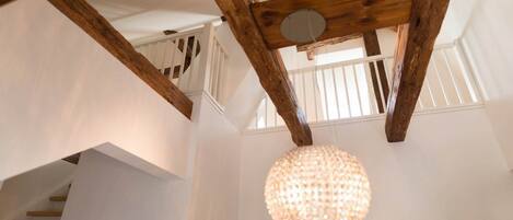 A staircase with wooden beams and a chandelier.