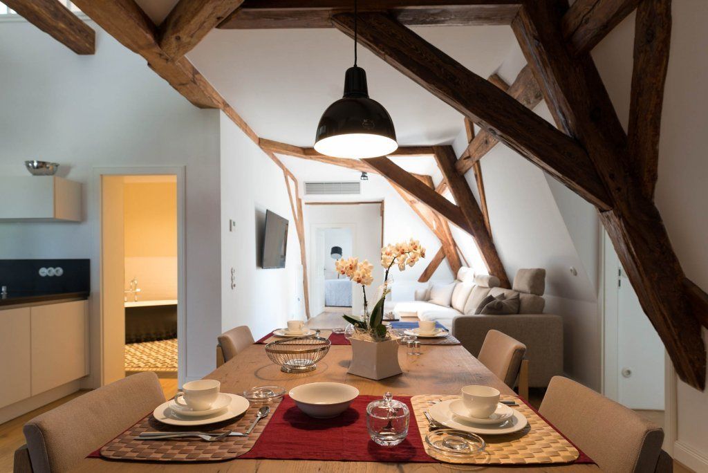 Een eetruimte met een houten plafond, een tafel gedekt voor vier personen en een vaas met bloemen.