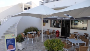 Un área de café al aire libre con mesas y sillas, una escalera y un cartel que anuncia té Lipton.