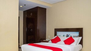 Een hotelkamer met een groot bed, een houten garderobe en een nachtkastje met een telefoon.