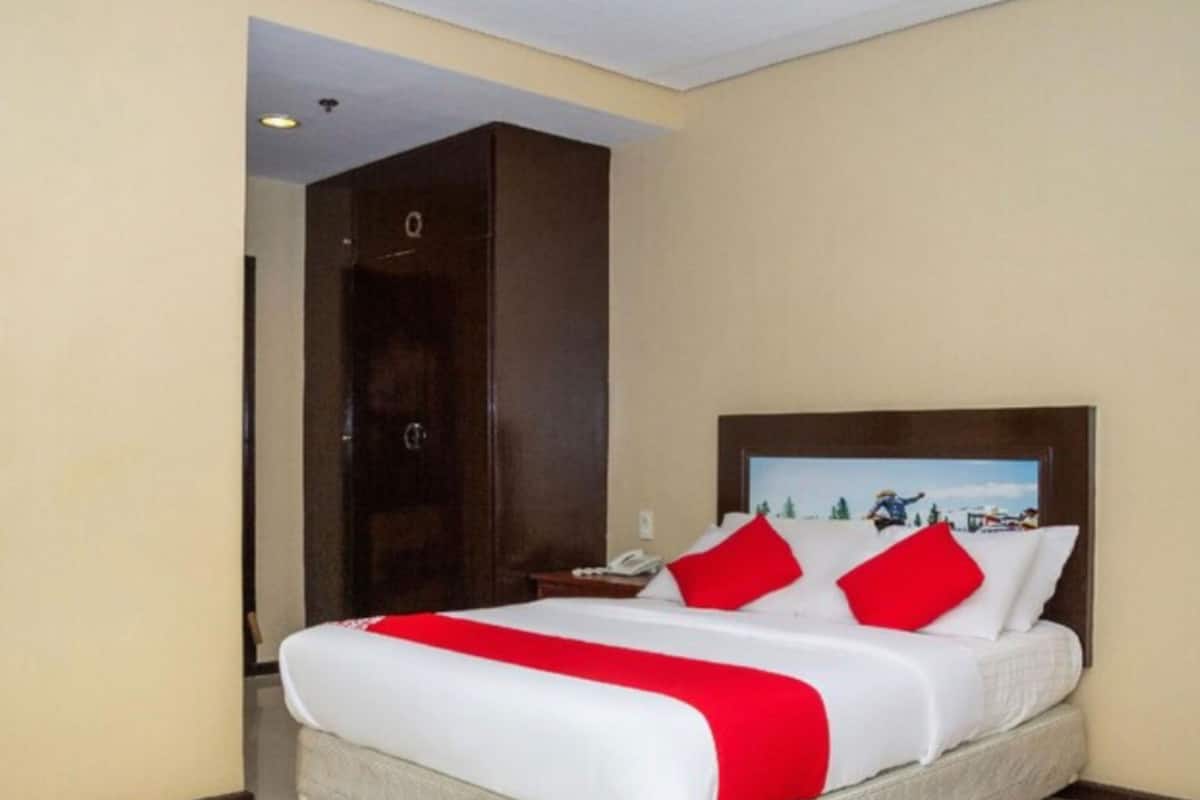 Ein Hotelzimmer mit einem großen Bett, einem Holzschrank und einem Nachttisch mit Telefon.