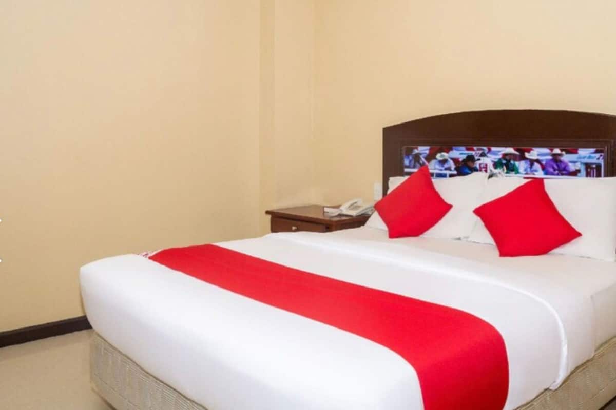 Ein Hotelzimmer mit Bett, Nachttisch und Fernseher an der Wand.
