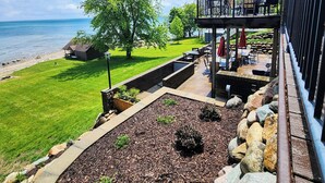 Une terrasse avec des sièges extérieurs, une vue sur la mer et un espace gazonné avec un arbre.