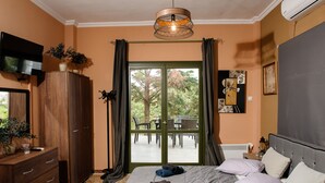 Un dormitorio con cama, armario, televisor y vista a un patio exterior.