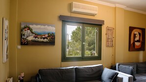 Una sala de estar con un sofá, un ventanal con vistas y obras de arte en las paredes.
