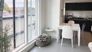 Eine moderne Wohnung mit Essbereich, kleiner Küche und großem Fenster mit Blick auf die Stadt.