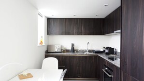 Eine moderne Küche mit dunklen Holzschränken, einer weißen Arbeitsplatte und einem eingebauten Backofen.