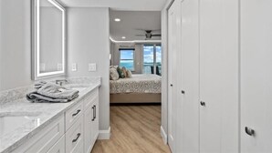 Quarto com uma cama grande, banheiro com toucador e vista para o oceano.