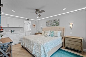 A bedroom with a bed, nightstands, a dresser, a ceiling fan, and a painting on the wall.