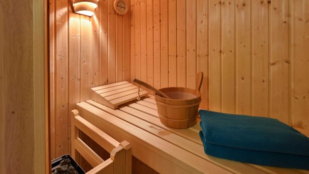 A sauna with wooden benches, a wooden bucket, and a towel.