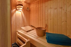 Eine Sauna mit Holzbänken, einem Holzfass und einem Handtuch.