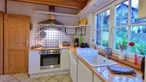 A compact kitchen with a built-in oven, a sink, and a window overlooking a garden.