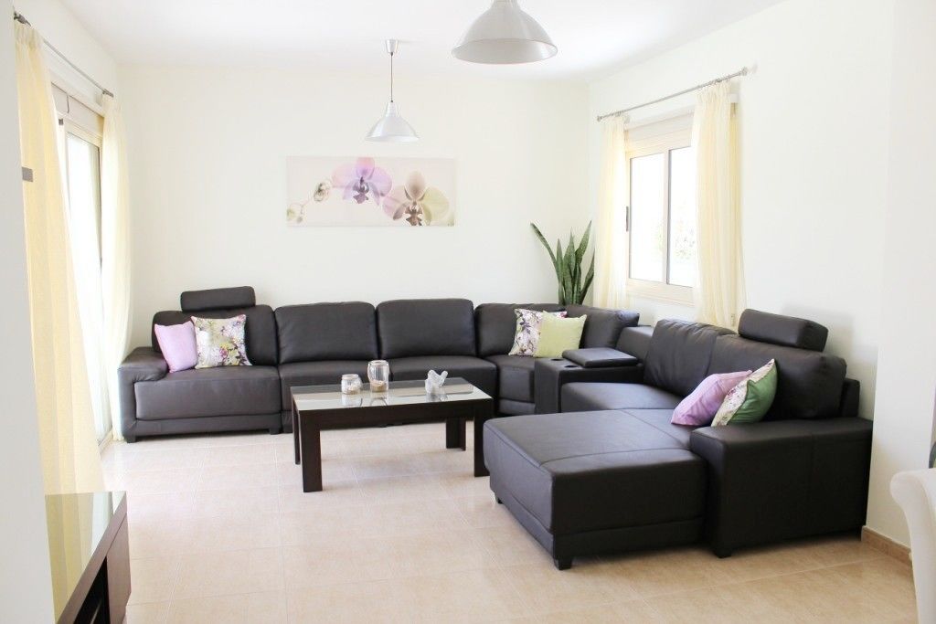 Ein modernes Wohnzimmer mit einem Ecksofa, einem Couchtisch und einer Pendelleuchte.