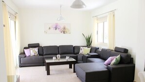 A modern living room with a sectional sofa, a coffee table, and a pendant light. - Villa Ksenia (Paralimni)