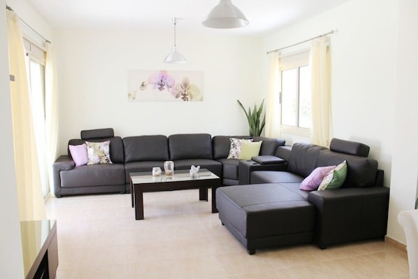 A modern living room with a sectional sofa, a coffee table, and a pendant light.