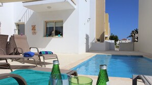 A poolside area with lounge chairs and a swimming pool. - Villa Ksenia (Paralimni)