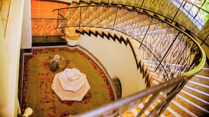 Un escalier en colimaçon orné de rampes en métal ouvragé et doté d’un sol à motifs.