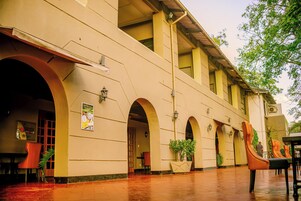 Un edificio con varios arcos, una zona exterior cubierta y arreglos de asientos.