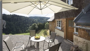 Eine Terrasse mit Tisch, Stühlen und einem großen Sonnenschirm.
