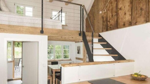 Eine moderne Küche mit einer Holzeinsel, einem eingebauten Ofen und einer Treppe, die in eine obere Ebene führt.