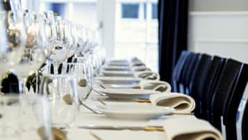 Una larga mesa de comedor dispuesta con numerosos vasos, platos y cubiertos, lo que sugiere un ambiente de comedor formal.