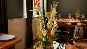 Une table à manger avec un vase de fleurs, un verre à vin et une assiette.