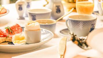 A breakfast setting with a plate of food, a cup, and a teapot.