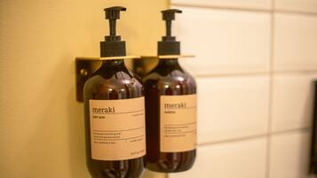 Two bottles of Meraki body wash on a wall-mounted dispenser.