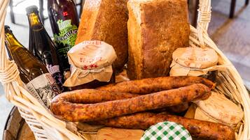 Una cesta de mimbre con diversos alimentos, como salchichas, pan y queso.