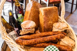 A wicker basket containing various food items including sausages, bread, and cheese. - Pałac Spichrz (Somonino)