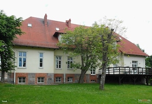 A two-story house with a red-tiled roof, multiple windows, and a brick foundation. - Pałac Spichrz (Somonino)