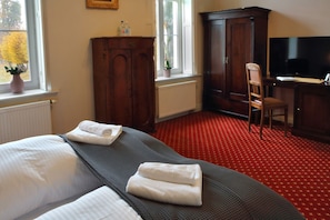 A hotel room with a bed, a desk, a television, and a wardrobe. - Pałac Spichrz (Somonino)