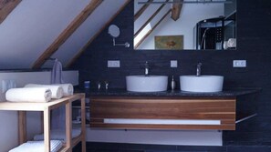 A modern bathroom with two sinks, a wooden vanity, and a mirror.