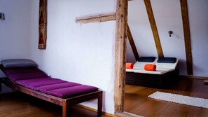 A room with a wooden bed, a small table, and a bench with cushions.