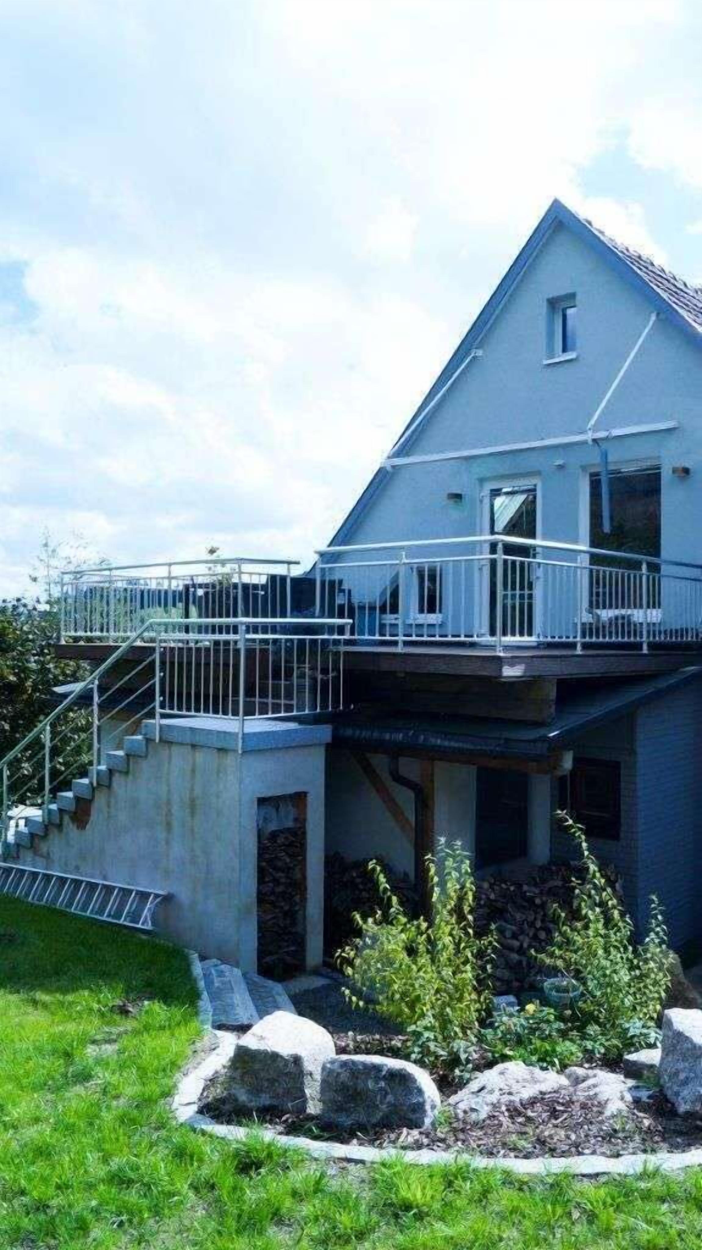 Ein zweistöckiges Haus mit Balkon, Treppe und Stein Fundament.