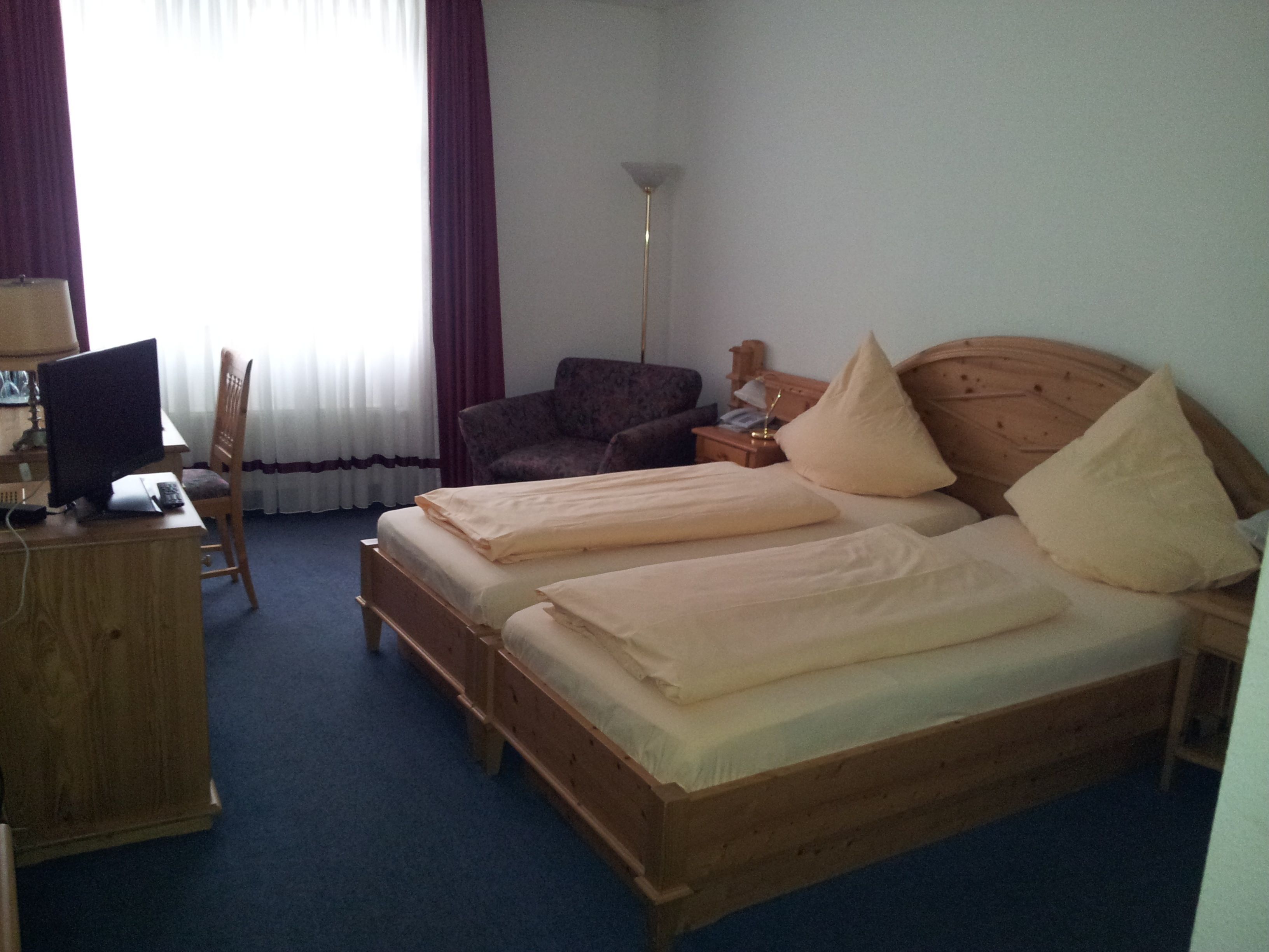 A room with a bed, a desk, a chair, and a lamp.