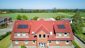 Ein zweistöckiges Haus mit rotem Dach, Solaranlagen und einer großen Haustür.