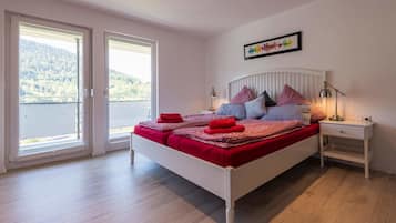 A bedroom with a bed, two bedside tables, a window, and a door.