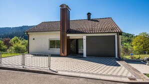 Une maison à deux étages, avec un toit en tuiles, une cheminée et un garage.