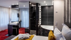 Una habitación de hotel moderna con cama, escritorio, ducha y baño.