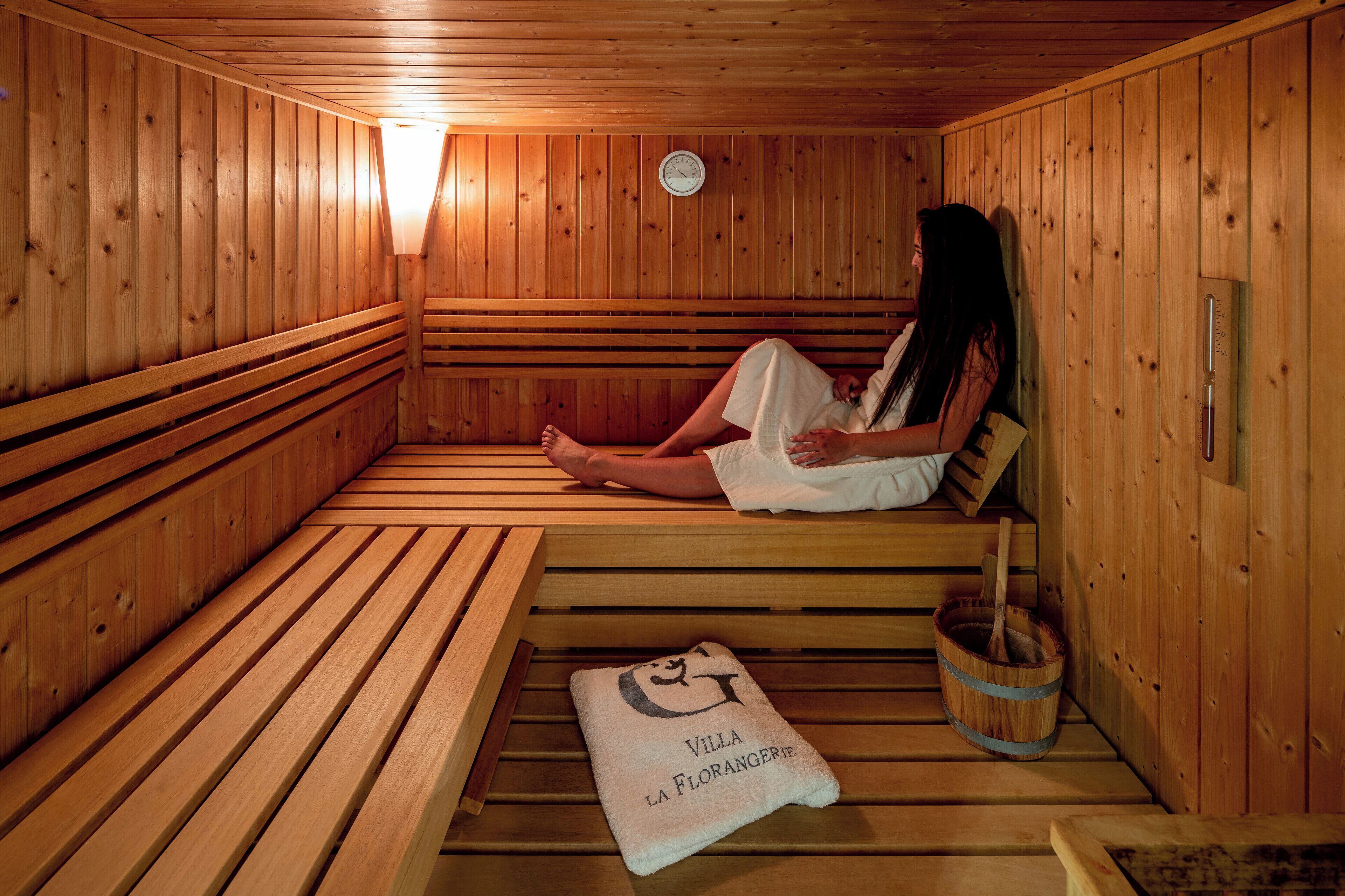 A wooden sauna with benches, a towel, and a bucket.