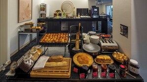 Un bufé de desayuno con diversos pasteles, panes y rellenos.