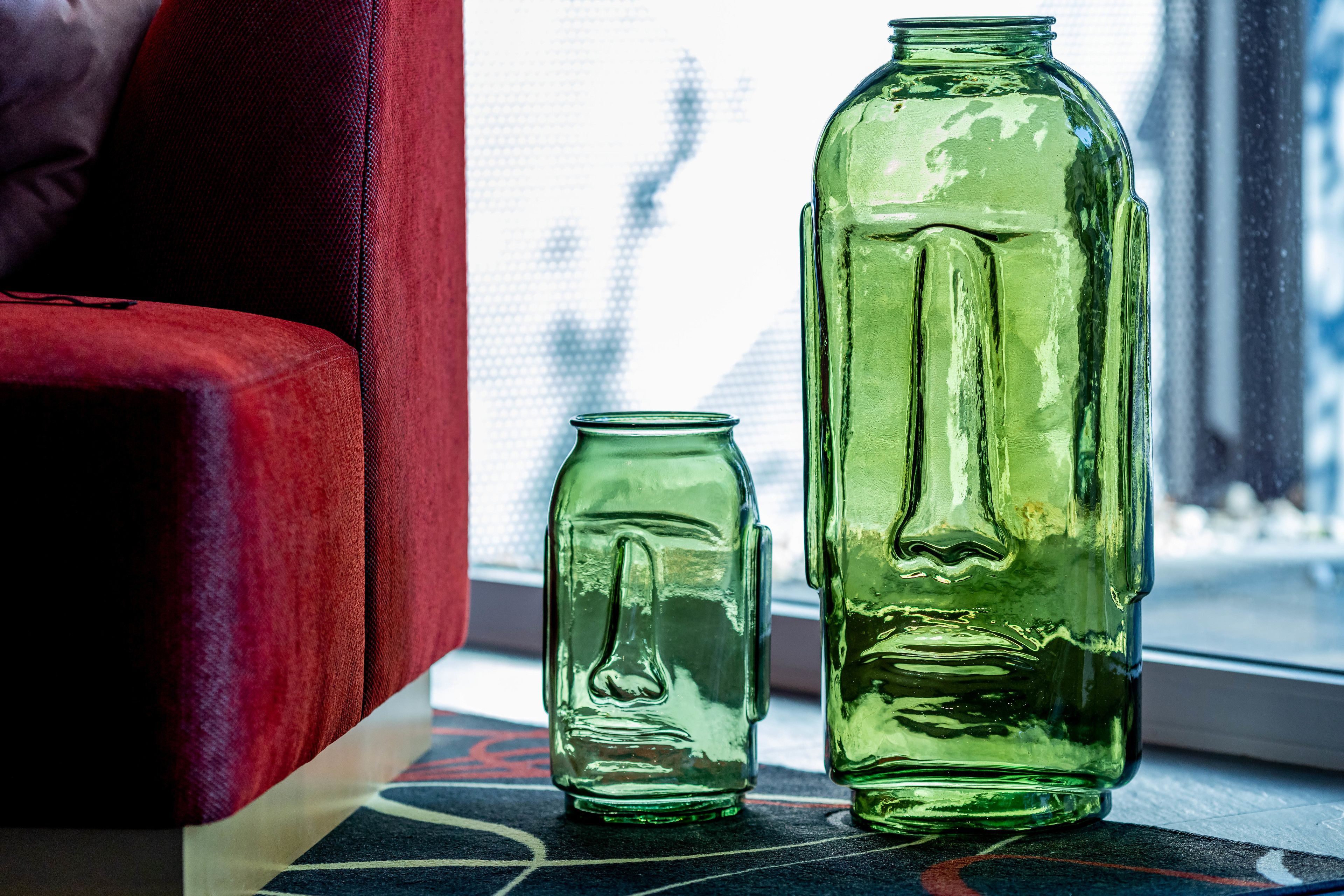 Two green glass bottles of different sizes on a windowsill.
