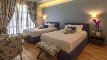 A hotel room with two beds, a chair, and a bench.